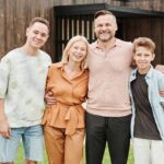 Smiling family of four posing outdoors, capturing love and togetherness.