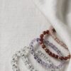 Crystal bracelets with clear quartz, amethyst, cinnabar and agate beads on a linen background