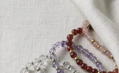 Crystal bracelets with clear quartz, amethyst, cinnabar and agate beads on a linen background